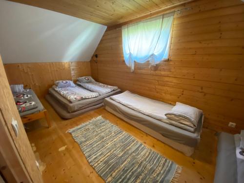 two beds in a wooden room with a window at Mooni Cottage in Pärnu