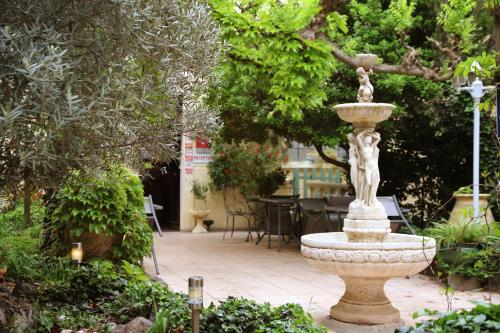 a fountain in the middle of a garden at Les jardins du Patriarche Hôtel in Agde