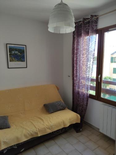 une chambre avec un canapé jaune devant une fenêtre dans l'établissement T2/T3 à sanary sur mer avec piscine, à Sanary-sur-Mer