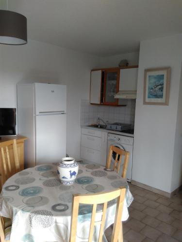 une cuisine avec une table et un réfrigérateur blanc dans l'établissement T2/T3 à sanary sur mer avec piscine, à Sanary-sur-Mer
