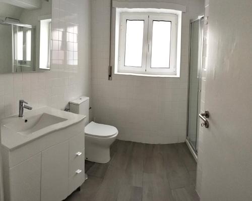 a bathroom with a toilet and a sink and a window at Casas da Cacilda II in Nazaré