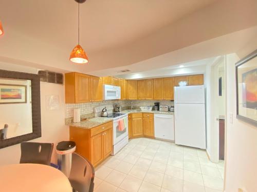 a kitchen with wooden cabinets and a white refrigerator at COMFY Basement Home 2 Bdrm1Den 3Queen Beds in Washington, D.C.