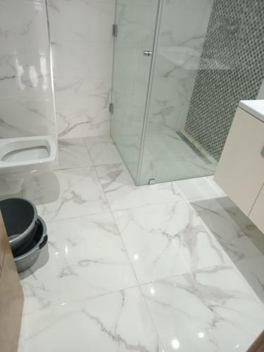 a bathroom with a shower and a white marble floor at Residence de la plage in Port El Kantaoui