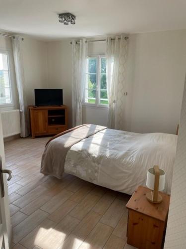 a bedroom with a bed and a television in it at Maison au sein d’un corps de ferme. in Carpiquet