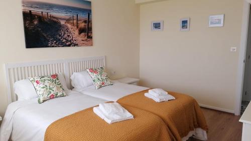 una camera da letto con un letto e asciugamani di Precioso piso en playa America con jardin privado. a Nigrán
