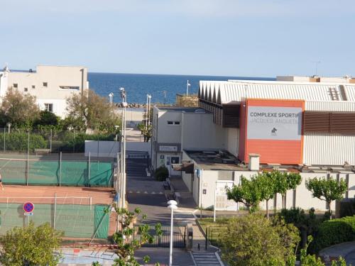 un edificio con una pista de tenis delante en Studio Carnon bord de plage climatisé, en Carnon-Plage