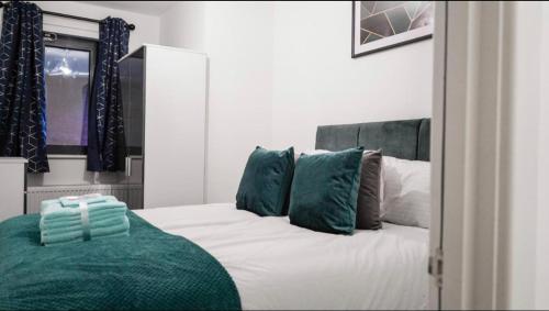 a bedroom with a white bed with green pillows at Two bedrooms, two bath, up to 3 beds 1 sofa - Slough Windsor Legoland in Slough