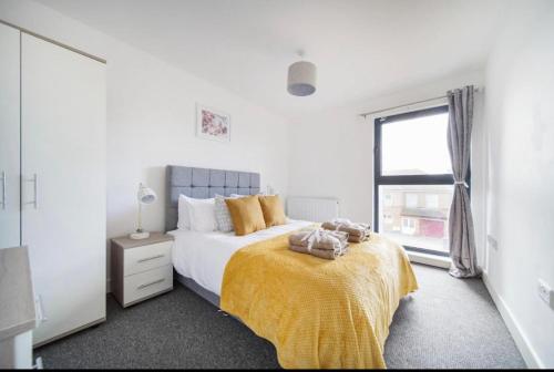 a bedroom with a bed with a yellow blanket and a window at Two bedrooms, two bath, up to 3 beds 1 sofa - Slough Windsor Legoland in Slough