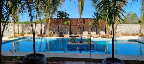 a swimming pool with palm trees in front of a building at Salama & Mbuyuni Bungalows in Matemwe