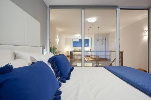 a bedroom with a large white bed with blue pillows at Seagull Luxury Maisonette in Itea