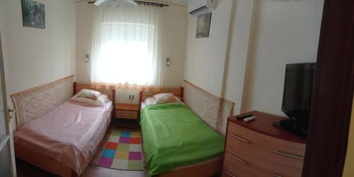 a room with two beds and a television and a window at Kámán Nyaraló in Badacsonytomaj