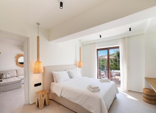 a white bedroom with a bed and a patio at Anemones Villas by Omikron Selections in Spanokhórion