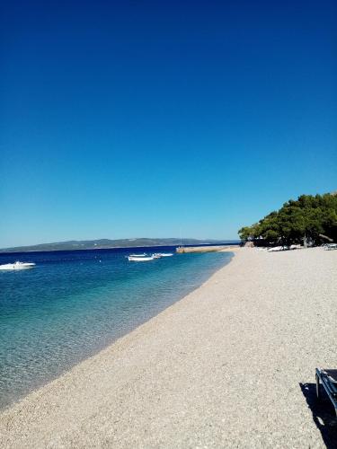 a sandy beach with two boats in the water at Apartment Hortenzija in Baška Voda