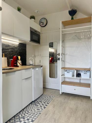 une cuisine avec des placards blancs et une horloge murale dans l'établissement Le Cocon Urbain, à Rennes