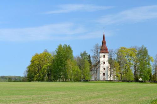 an old building with a tower in a field at Torma Puhkemaja ja Glämping in Torma