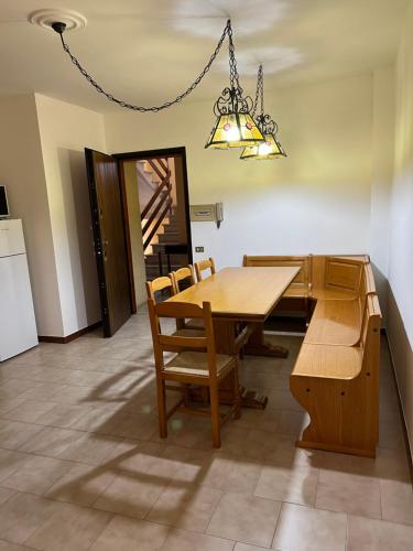 een eetkamer met een tafel en stoelen en een kroonluchter bij Maison De Plage in Sabaudia