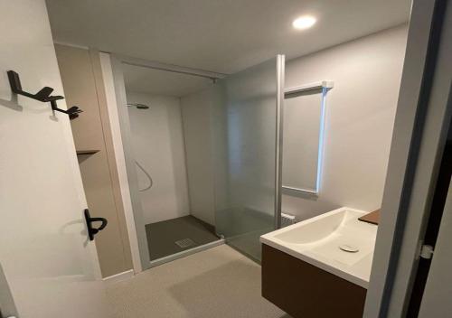 La salle de bains est pourvue d'une douche en verre et d'un lavabo. dans l'établissement Charmant dans camping 5 étoiles-lac, à Biscarrosse