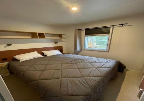 a bedroom with a large bed and a window at Charmant dans camping 5 étoiles-lac in Biscarrosse