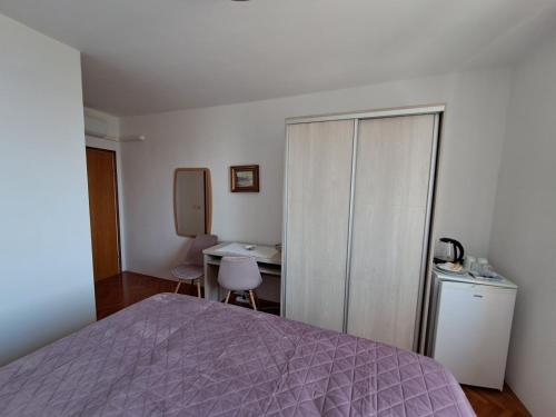 1 dormitorio con cama, escritorio y mesa en Old town rooms, en Rab