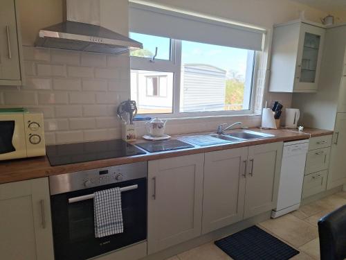 a kitchen with white cabinets and a sink and a window at Radharc an tSléibhe - Mountain View - Eircode F92R2R8 in Letterkenny