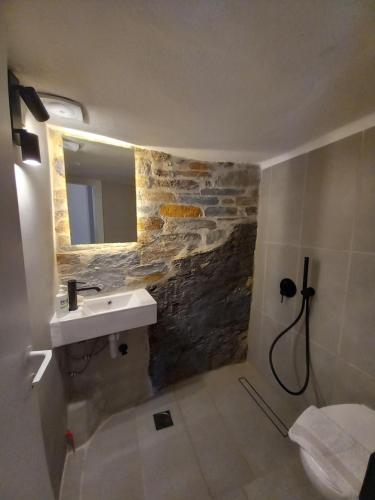Un baño con lavabo y pared de piedra. en Στη Μεσσάδα... Sti Messada..., en Ioulida