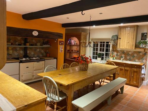 a kitchen with a wooden table and chairs at Mid-Wales Farmhouse, swimming pool, tranquil countryside views, sleeps 14 in Meifod