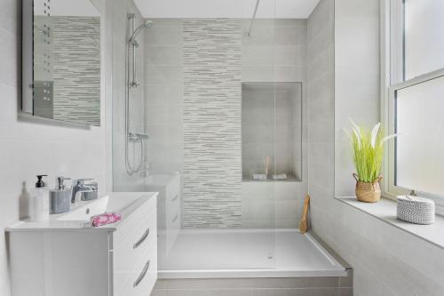 a white bathroom with a tub and a sink at Rutland Heights - Luxury Apartment in Torquay