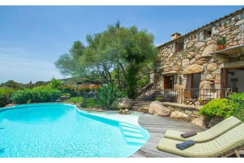 - une piscine avec 2 chaises longues et une maison dans l'établissement Les Lauriers Roses Palombaggia Porto-Vecchio, à Porto-Vecchio