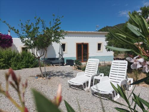 dos sillas blancas sentadas frente a una casa en Can Pep Pardal en Sant Miquel de Balansat