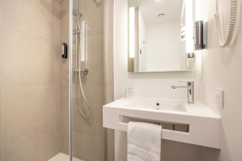 a white bathroom with a sink and a shower at B&B HOTEL Namur in Namur