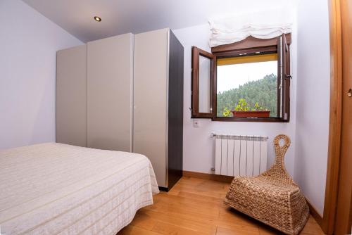 1 dormitorio con cama, ventana y silla en Cerezal 3, Loft en plena naturaleza, en Llanes