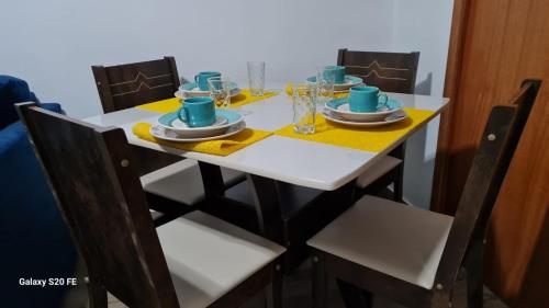 una mesa con sillas y una mesa blanca con platos y tazas en Apartamento Sandy-Zona Sul en Río de Janeiro