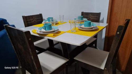 a table with chairs and a white table with plates and cups at Apartamento Sandy-Zona Sul in Rio de Janeiro