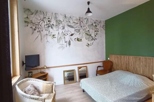 ein Schlafzimmer mit einem Bett, einem Stuhl und einem TV in der Unterkunft Le Raffiné in Millau