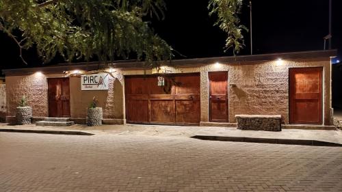 a building with two garage doors and a sign that reads pray at Pirca Hostal in San Pedro de Atacama