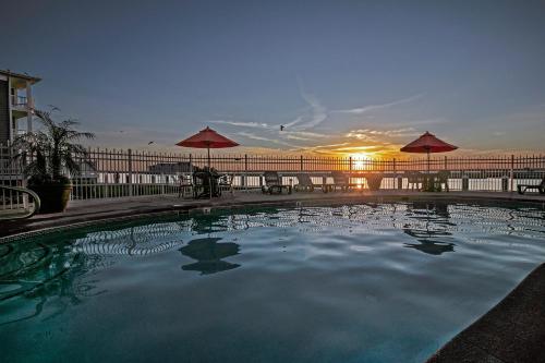 a large swimming pool with a sunset in the background at Comfort Suites Chincoteague Island Bayfront Resort in Chincoteague