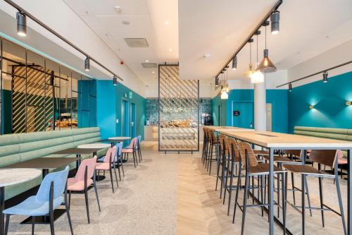 a restaurant with blue walls and tables and chairs at B&B HOTEL Namur in Namur