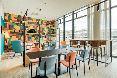 een restaurant met tafels en stoelen en een muur van ramen bij B&B HOTEL Namur in Namen