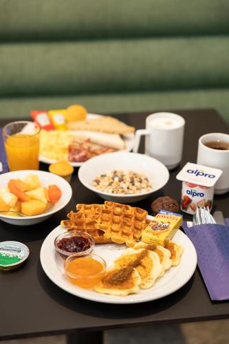 a table topped with plates of breakfast foods and drinks at B&B HOTEL Namur in Namur