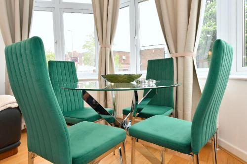 a dining room with green chairs and a glass table at Hendon Escape Luxury Apartment with En-suite Bath in Hendon