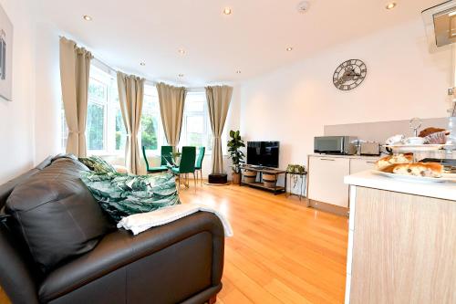 a living room with a leather couch and a kitchen at Hendon Escape Luxury Apartment with En-suite Bath in Hendon
