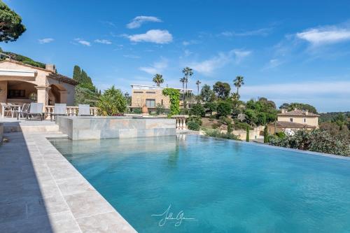 une piscine avec de l'eau bleue devant une maison dans l'établissement Villa Loubliere, à La Roquette-sur-Siagne