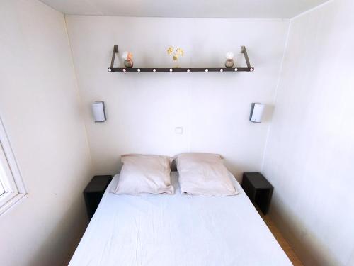a small bedroom with a bed and two pillows at Domaine des Iscles in La Roque-dʼAnthéron