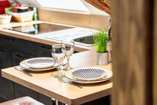 SOUS LE HAUT DES REMPARTS في بون: طاولة عليها كأسين وصحون في مطبخ