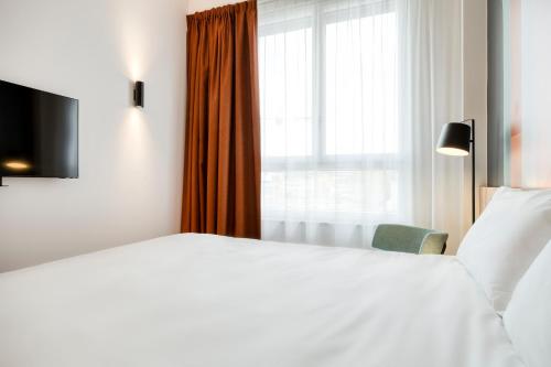a bedroom with a white bed and a window at B&B HOTEL Namur in Namur