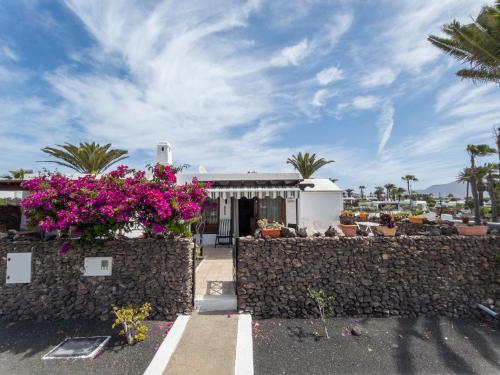 una casa con flores frente a una pared de piedra en Casas del Sol en Playa Blanca