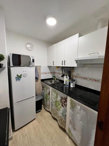 a kitchen with white cabinets and a refrigerator at Edificio Playa in Las Palmas de Gran Canaria