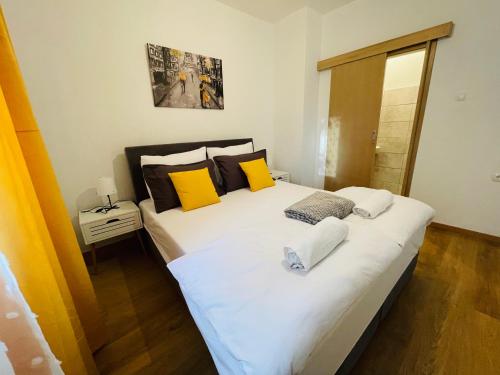 a bedroom with a large white bed with yellow pillows at Apartmani Roko&Lovre Paklenica in Starigrad
