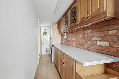 a kitchen with wooden cabinets and a brick wall at Wheelbarrow Cottage in Bengeworth