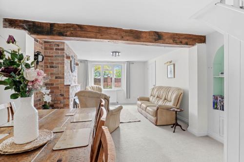 a kitchen and living room with a table and chairs at Wheelbarrow Cottage in Bengeworth